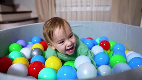 Smiling Infant Lying in Colorful Ball Pit