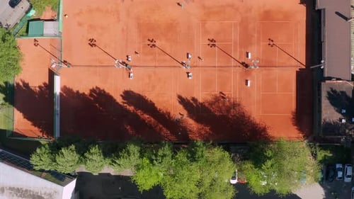 Top View Of People Playing Tennis At An Outdoor Tennis Court In Novi Sad, Serbia On A Sunny Morning.