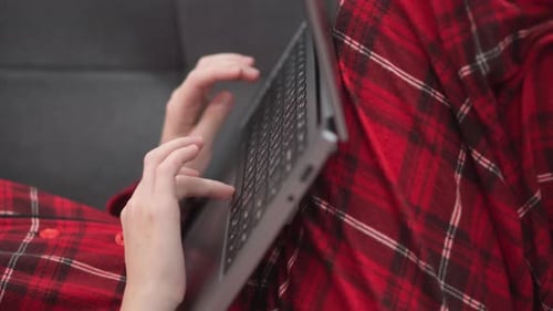 Woman in Red on Sofa at Home with Laptop Christmas Tree and Gifts