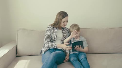 Woman and Child Interact with Tablet on Couch