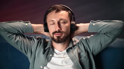 Pleasant Male Listening Music Headphones Stress Free Relaxing Lying with Hands Behind Head