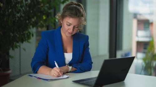 Young Female Office Employee Working at a Computer While Sitting at a Table