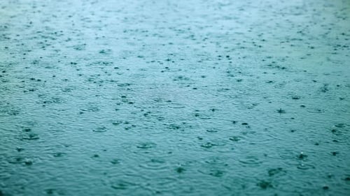 Regen, der auf die Wasseroberfläche fällt und Wellen in Zeitlupe erzeugt