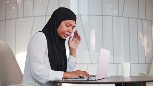 Tired Woman in Hijab Having Headache During Work on Laptop at Modern Office