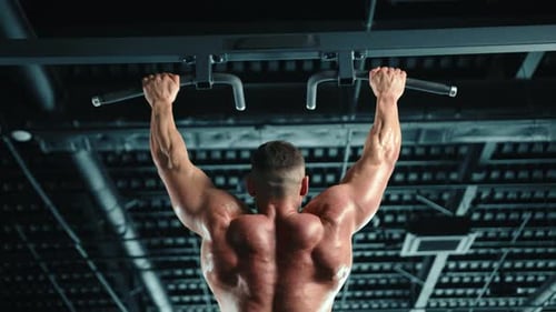 Muscular Man Performing PullUps on Horizontal Bar in Modern Fitness Center