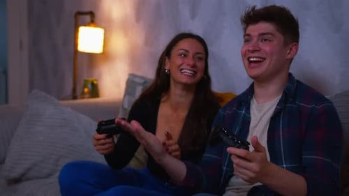 Smiling Couple Playing Video Games Together on Sofa