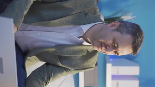Vertical Video of Smiling mature man using smartphone indoors.