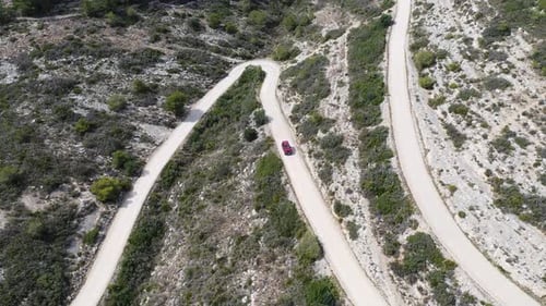 Aerial View of Car Driving Along a Winding Dusty Road – 4K Drone Video