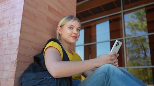 Smiling Woman Using Smartphone on College Campus