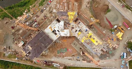 Aerial view of workers and cranes working on construction site.