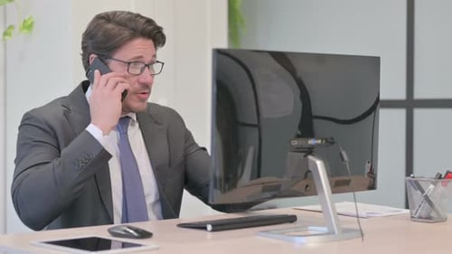 Businessman Talking on Phone at Office Desk