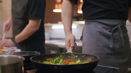 Restaurant Chef Adding Salt and Tossing Mixed Vegetables in Frying Pan