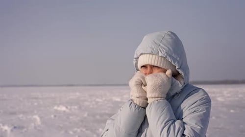 Eisende Frau wärmt Hände in Winterlandschaft