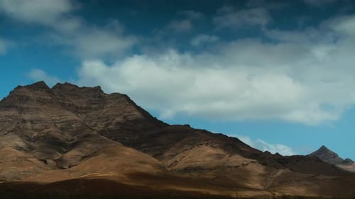 Timelapse of rocky mountains with clouds crossing the wind.