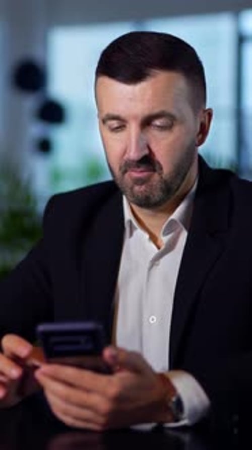 Man in Blazer Using Phone at Table