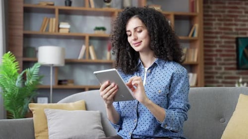 Woman Using Tablet Device on Couch Indoors