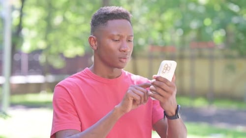 Young Man Using Smartphone Device in Park