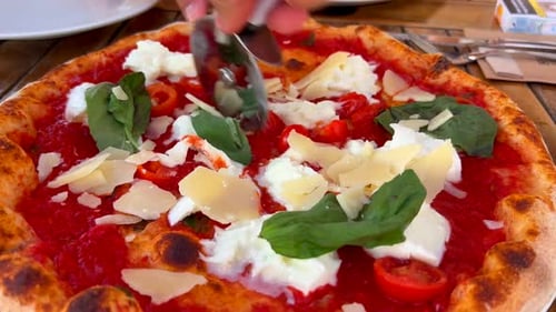 Cutting Pizza with Tomato Sauce and Cheese Toppings