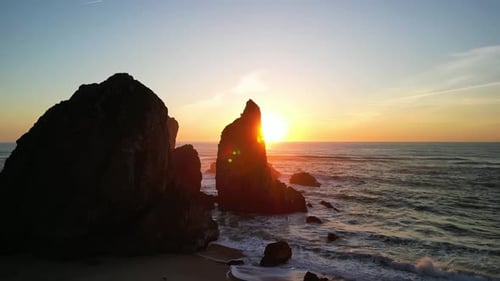 Witness the Stunning Sunset Illuminating the Rocky Seashore and Waves Crashing Against Cliffs