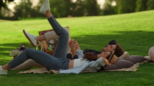 Romantic Couple Lying on Blanket at Green Grass and Holding Hands On