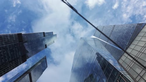 View From Below Showcases Tall Contemporary Glass Skyscrapers Set Against a Backdrop of Blue Cloudy