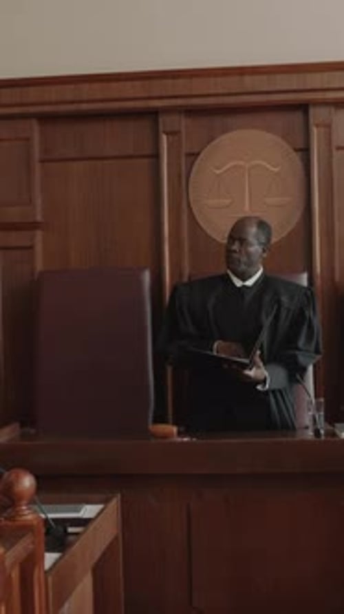 Mature Male Judge Looking at Court Participants and Passing Decision