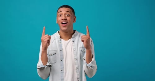 Young African American Man Point Index Fingers Up on Something Gesture on Blue Studio Background