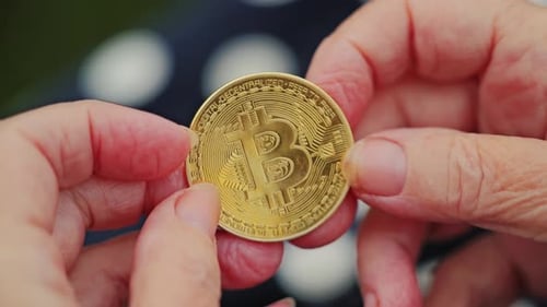 Aged Fingers Hold Bright Gold Bitcoin Coin in Soft Light – Slow Motion View