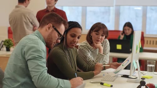 Equipe de negócios multiétnica focada: pessoas discutindo sobre o uso de computadores desktop no local de trabalho africano