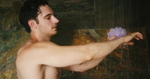 Young Man Takes Shower Using Washcloth to Wash Body Smiling