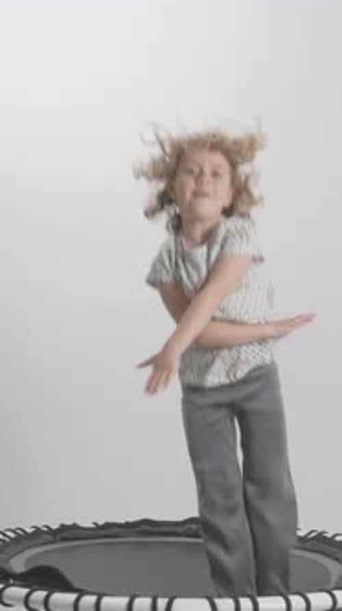 Happy Child Jumps on Trampoline Indoors