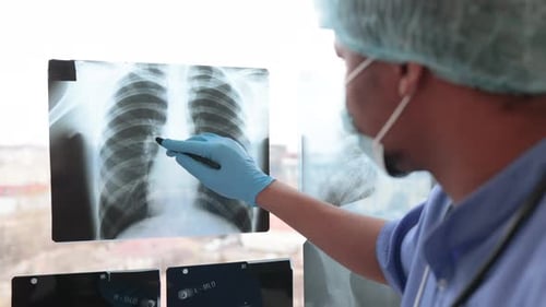 Doctor in Mask and Cap Standing with Tablet Near Body Scans
