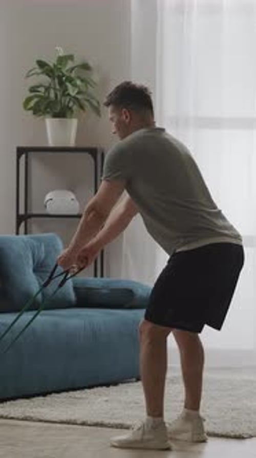 Focused Man Performing Resistance Band Workout in Modern Living Room Engaging in Functional Home