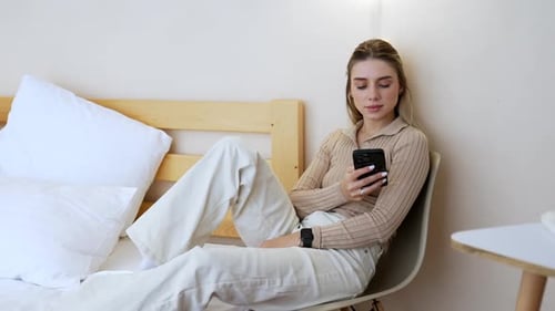 Woman Using Smartphone While Relaxing in Modern Home