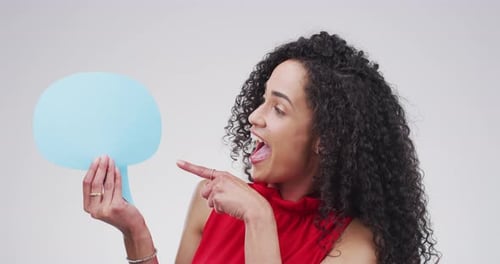 An attractive young woman holding up a speech bubble against a grey background