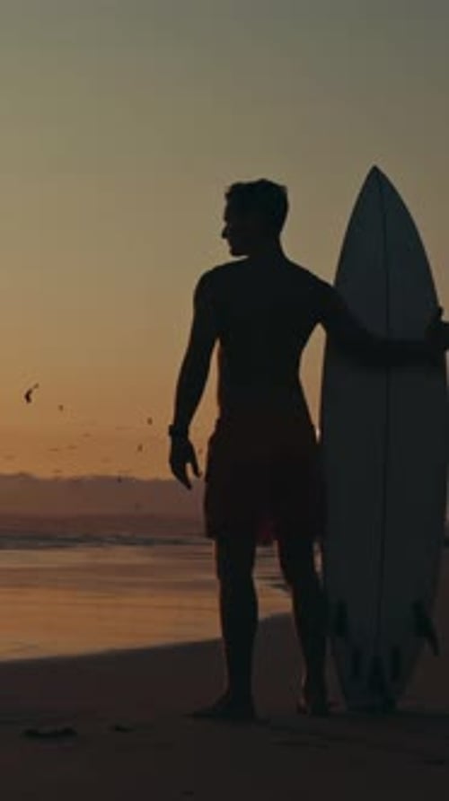 Ein attraktiver nachdenklicher Surfer steht am Ufer von