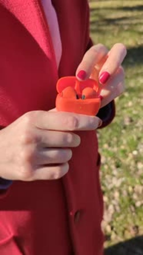 Person Opening Earbud Case Outdoors