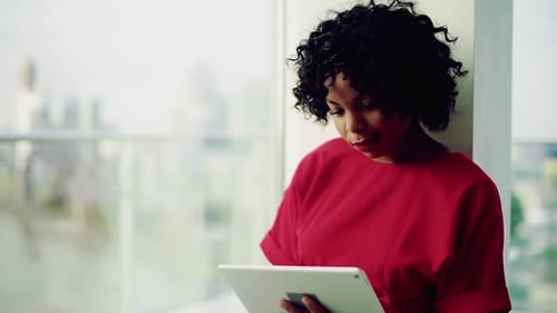 A Woman Standing by the Window Against London Panorama, Using Tablet