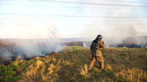 Young Fireman in Full Equipment Talking on Walkietalkie on Place at Fire Outdoor Male Professional
