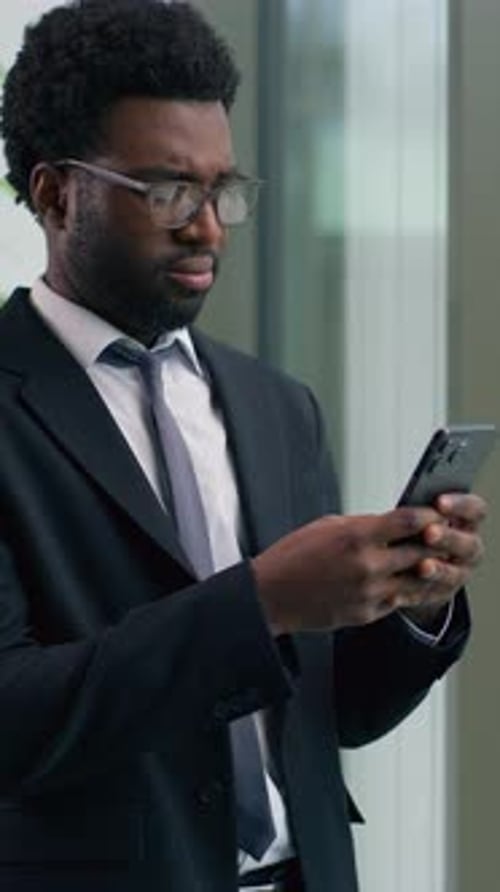 African American Businessman Looking Serious at Smartphone Reading Bad News Texting Using Mobile