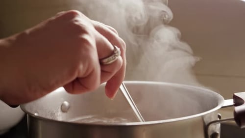 Slow motion of woman stirring hot soup in pot