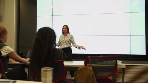 Enthusiastic lecturer explaining lesson to students in university classroom