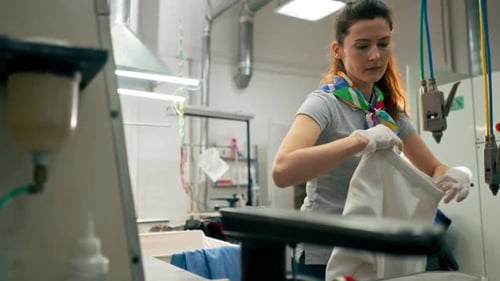 Woman Cleaning Garment in Industrial Laundry Setting