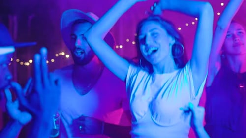 Excited Friends Dancing Together at Night Party