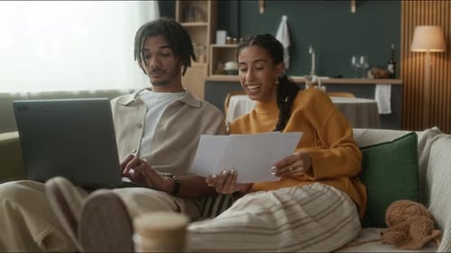 Couple Relaxing on Couch with Laptop and Papers
