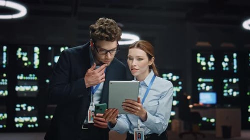 Hombre, mujer, técnicos de servidores trabajando con una computadora portátil en un centro de datos nocturno, primer plano