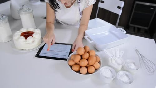 Woman Using Tablet Baking with Cake Ingredients