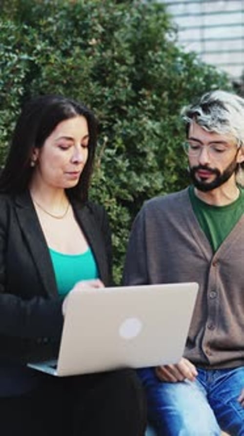Business people sitting outside the office having a business meeting and using a laptop computer.