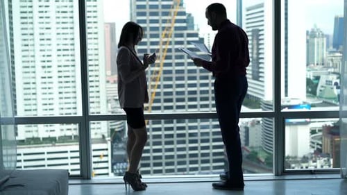 Businesspeople Working with Smartphone and Documents Standing by Window in Office Adult