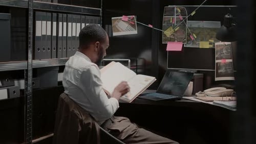 Man Reviews Files in Office at Laptop